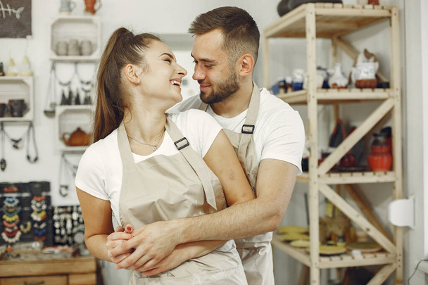 Young couple at standing in pottery with ceramic dishes - Foto, imagen