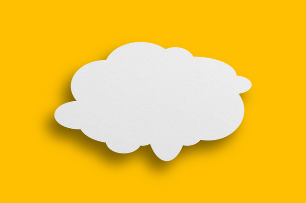 Weißes Papier in Sprechblasenform vor gelbem Hintergrund. Kommunikationsblasen. - Foto, Bild
