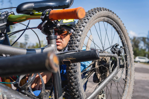Close-up of man with helmet and glasses preparing his mountain bike to do sports outdoors - 写真・画像
