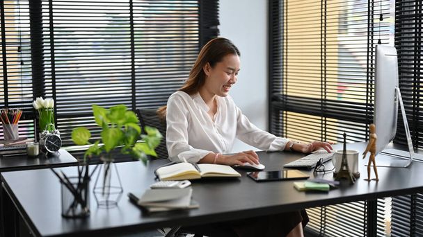 Uma empresária milenar asiática ou gerente feminina relaxa em seu escritório, gosta de trabalhar em seu projeto. - Foto, Imagem