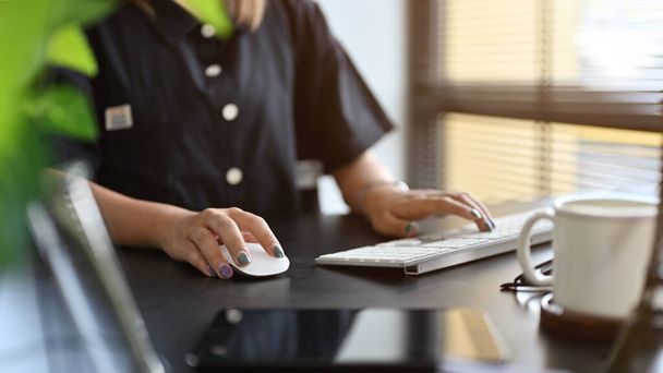 Kobieta pracownik lub pracownik biurowy siedzi przy biurku i pracuje na komputerze. przycięty obraz - Zdjęcie, obraz