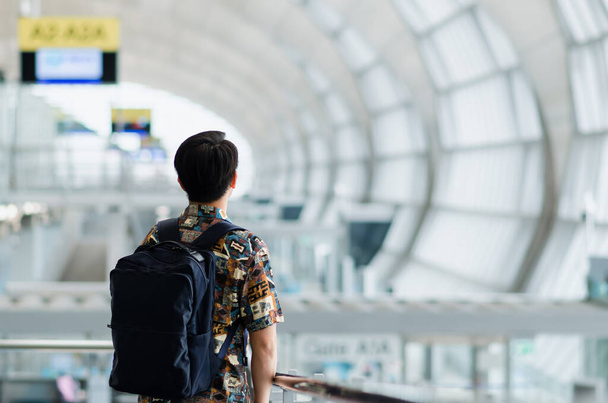Aziatische man met draagtas staan en kijken uit naar de luchthaven. Reis- en vakantieconcept. - Foto, afbeelding