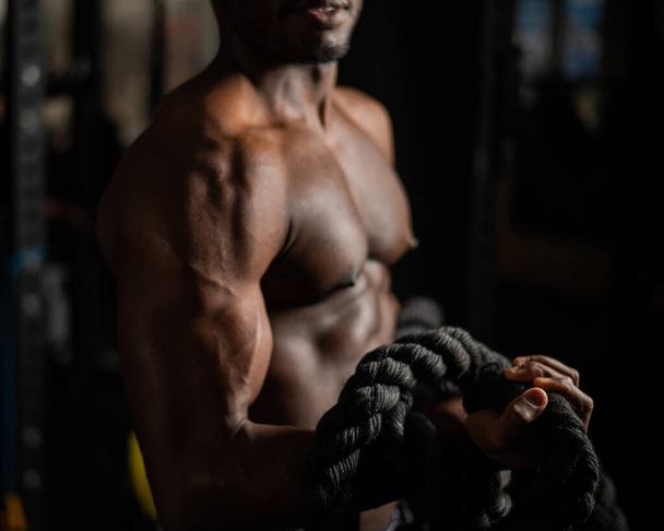 Muscular african american man posing with rope in gym.  - Foto, imagen