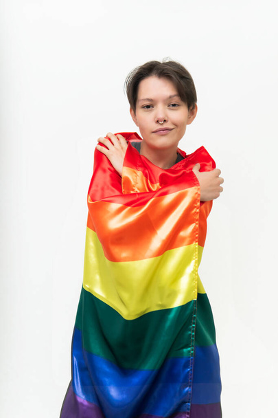 young girl involved in an lgbti icon flag looking at camera confident in front of a white background - Foto, Imagen