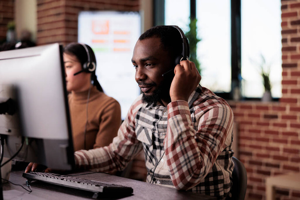 Operador de centro de llamadas afroamericano hablando con clientes en línea de ayuda - Foto, imagen