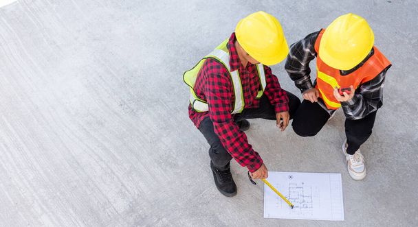 Architect and client discuss help create plan with blueprint of the building at construction site floor. Asian engineer foreman worker man and woman meeting talking on drawing paper project, top view - Foto, immagini
