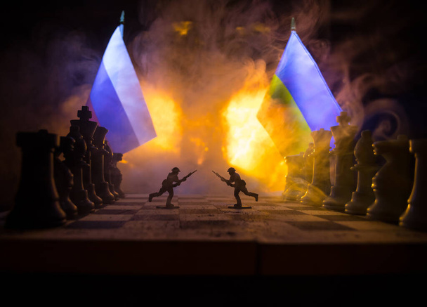 War between Russia and Ukraine, conceptual image of war using chess board, soldiers and national flags on the background of explosion. Ukrainian and Russian crisis. Selective focus - 写真・画像