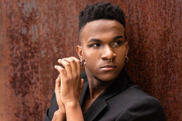 Portrait of a model man of black ethnicity in a fashion pose on a brown metallic background, seductive look - Valokuva, kuva