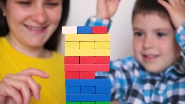 Mother and son play a board game, carefully pulling colorful blocks from the tower. - Záběry, video