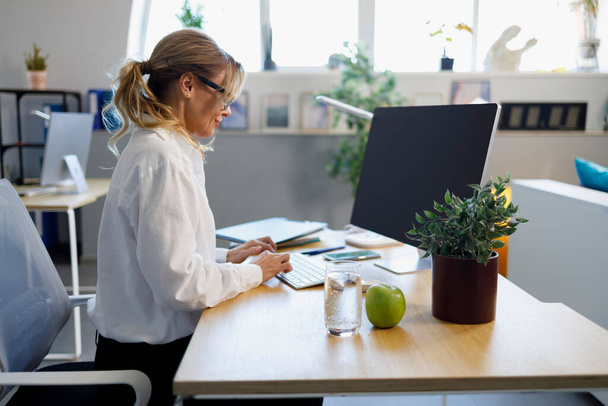 Élégante femme d'affaires mature travaillant sur ordinateur dans le bureau - Photo, image