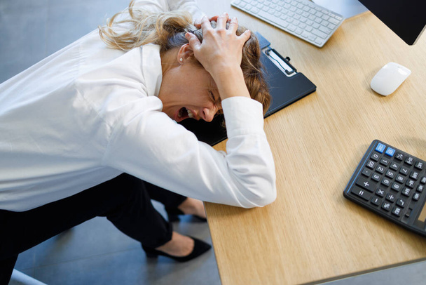 Depressed office worker holding her head and screaming, problems at work, to lose a job - Foto, imagen