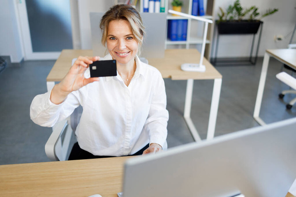 Femme d'affaires souriante montrant carte de crédit
 - Photo, image