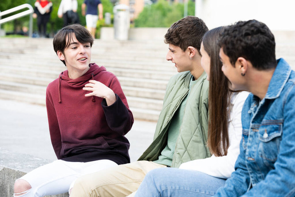 Cute teenager boy talking to his friends outdoors - Photo, Image