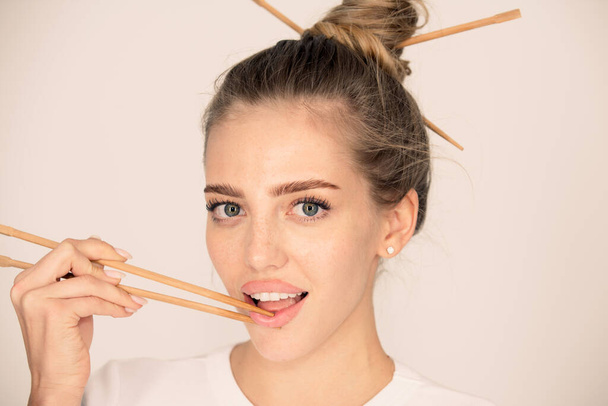 Sexy woman hand holding chopsticks near sexy lips mouth. Studio isolated portrait. - Фото, зображення