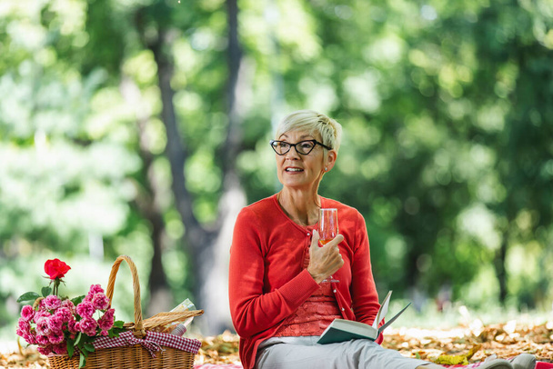 Portret starszej kobiety na pikniku w książce do czytania w parku - Zdjęcie, obraz