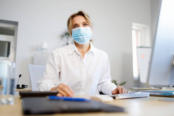 Portrait of a mature business woman in a medical mask - 写真・画像