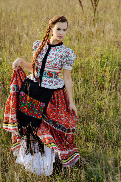 Young peasant woman, dressed in Hungarian national costume, posing over nature background - Photo, Image