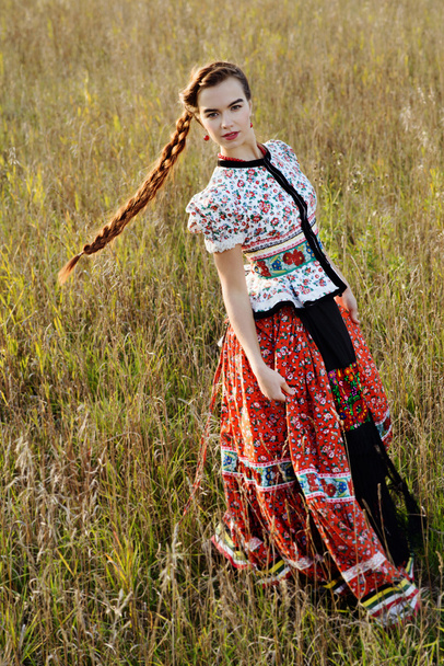 Young peasant woman, dressed in Hungarian national costume, posing over nature background - Zdjęcie, obraz