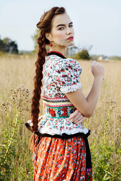 Young peasant woman, dressed in Hungarian national costume, posing over nature background - Valokuva, kuva