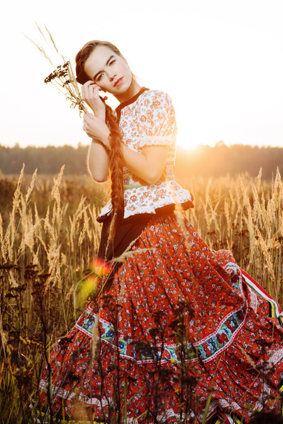 Young peasant woman, dressed in Hungarian national costume, posing over nature background - Foto, imagen