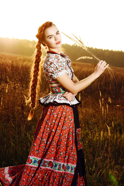 Young peasant woman, dressed in Hungarian national costume, posing over nature background - Foto, Imagem