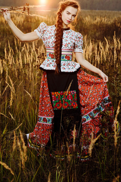 Young peasant woman, dressed in Hungarian national costume, posing over nature background - Fotografie, Obrázek