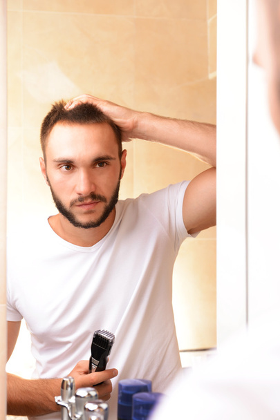 Young man shaving his beard in bathroom - Фото, изображение