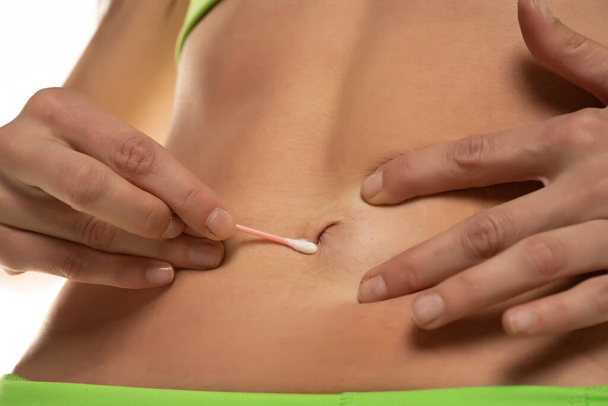 Woman cleaning her belly button with cotton swab , Cropped image, close up. - Foto, Imagen