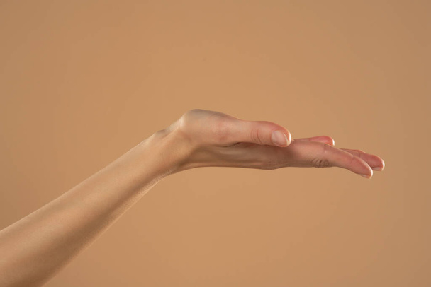 Weibliche Hand und offene Handfläche isoliert auf beigem Hintergrund. - Foto, Bild