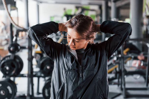 Young girl in black sportwear preparing for exercises in modern gym. - Valokuva, kuva