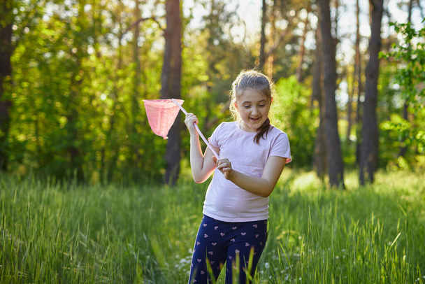 Little girl catches butterflies with a pink juice on a summer day - Fotografie, Obrázek