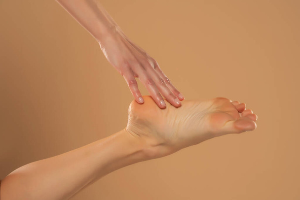 Pieds féminins parfaitement propres. Belle et élégante main de femme toilettée touchant son pied. Spa, gommage et soins des pieds - Photo, image