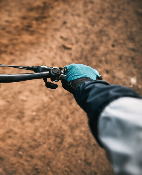 First-person view bicycle riding. Man riding a bike. holding bike handlebar with one hand in sport glove. Summertime outdoor leisure sport activity. Close up of bicycle handle bar - Foto, Bild
