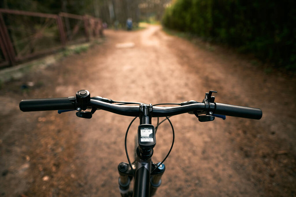 Vista superior do guidão de bicicleta de montanha e estrada de floresta de cross country turva. Conceito de atividade extrema nas trilhas da floresta. - Foto, Imagem