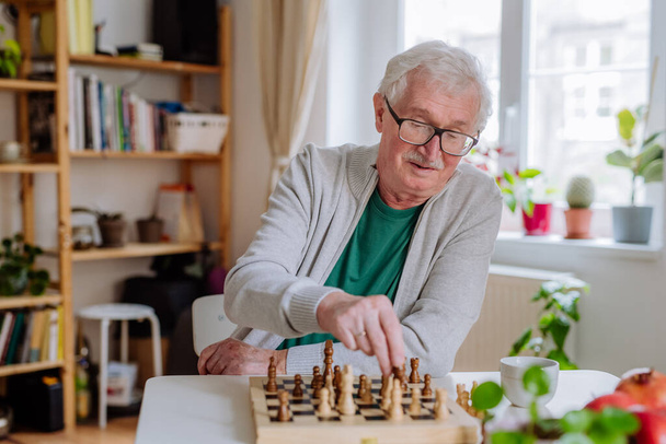 Senior man playing a chess at home. - Fotografie, Obrázek