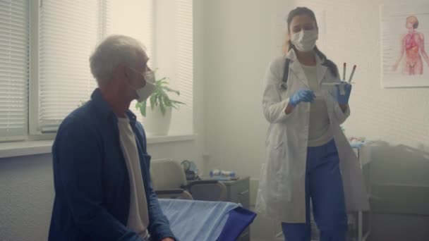 Latino dokter verzamelt speeksel monster senior man close-up. Covid-testconcept. - Video