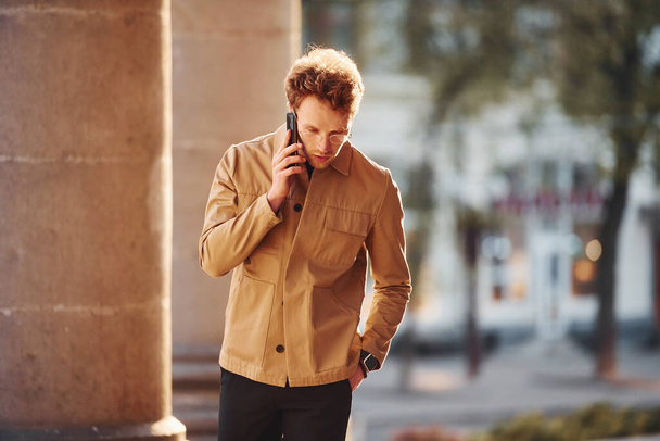 Talking by phone. Elegant young man in formal classy clothes outdoors in the city. - Foto, imagen