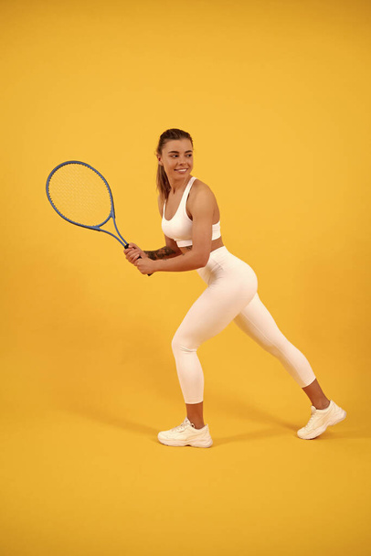 sonriente tenista correr con raqueta sobre fondo amarillo, deporte - Foto, Imagen