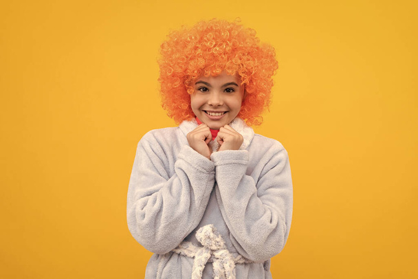 Süslü turuncu peruklu mutlu genç kız bornoz giyer, ev elbisesi giyer. - Fotoğraf, Görsel