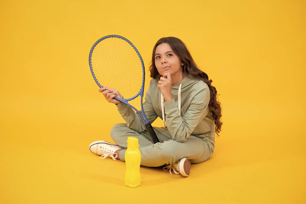 thinking child with tennis racquet. teen girl after sport training. dedicated to fitness. - Photo, Image