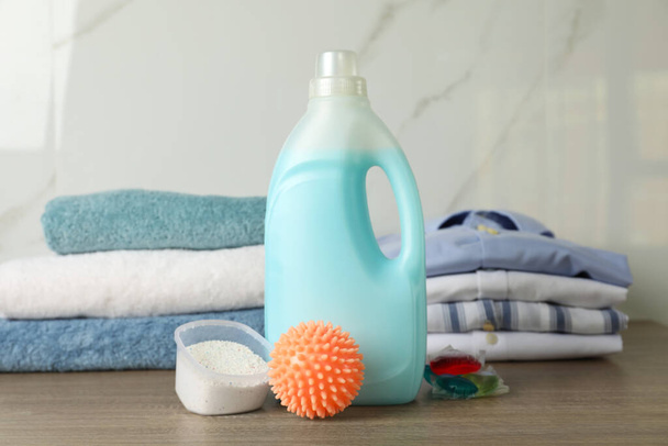Orange dryer ball, detergents, clean towels and clothes on wooden table - Fotó, kép