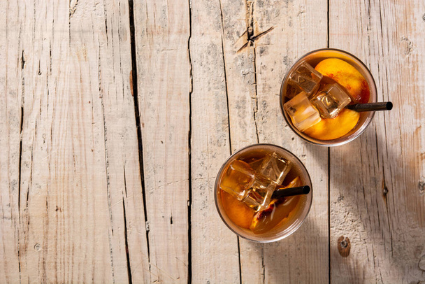 Glass of peach tea with ice cubes on wooden table. Top view. Copy space - Foto, imagen