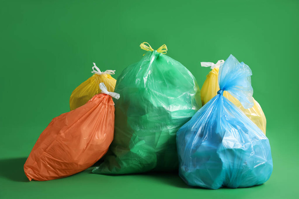 Trash bags full of garbage on green background - Foto, Imagem
