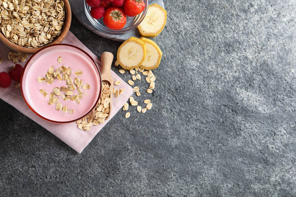 Glass of tasty berry smoothie with oatmeal on grey table, flat lay. Space for text - Photo, image