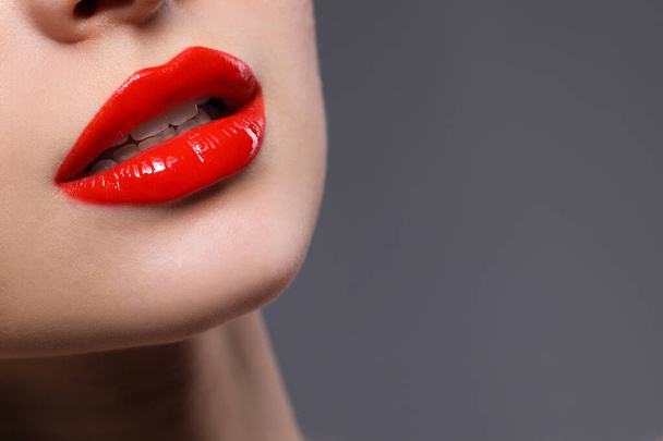 Young woman with beautiful red lips on grey background, closeup. Space for text - Fotó, kép