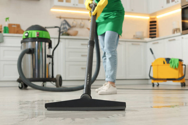 Professional janitor vacuuming floor in kitchen, closeup - Zdjęcie, obraz