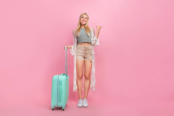 Full size photo of young blond lady with bag index promo wear top cape shorts sneakers isolated on pink background - 写真・画像
