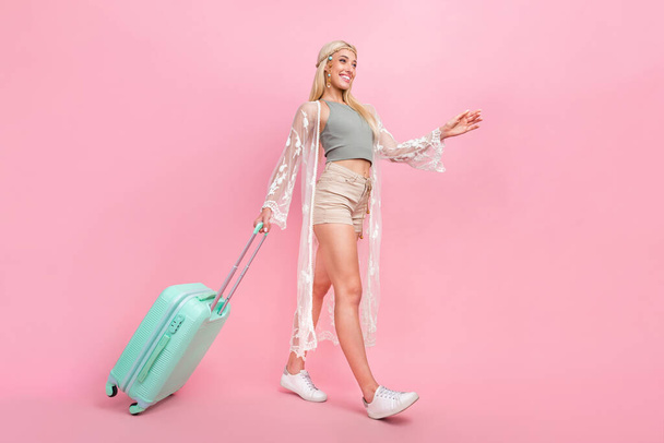 Full body photo of millennial blond lady go with bag wear top cape shorts sneakers isolated on pink background - Foto, imagen