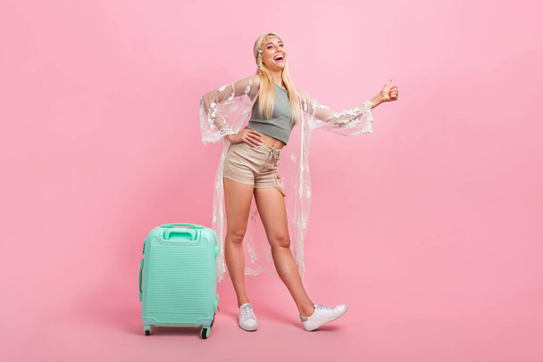 Full size photo of cute young blond lady stop car with bag wear top cape shorts shoes isolated on pink background - Photo, image