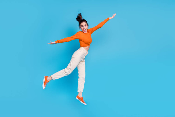Full size profile side image of excited cheerful playful female have fun jumping isolated on blue color background - Photo, image